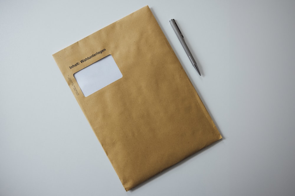 um envelope marrom com uma caneta em cima