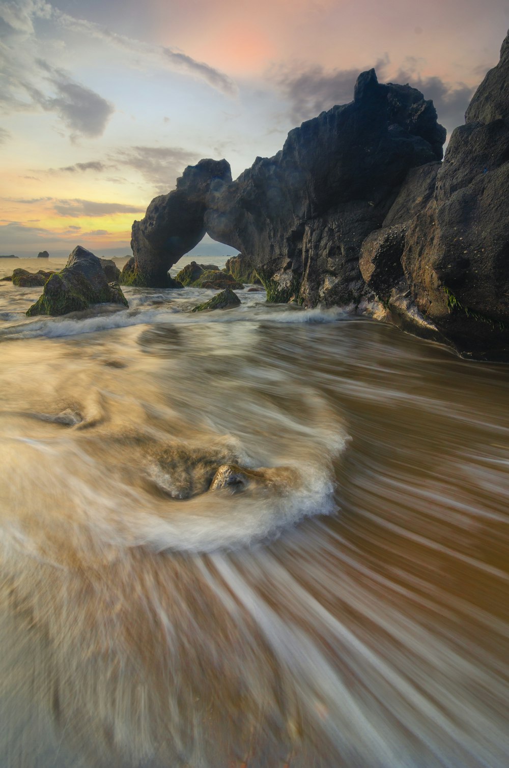 a beach with a rock formation in the background