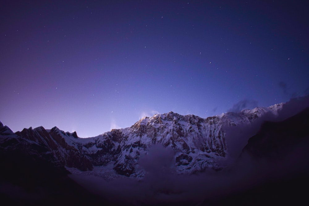 a mountain covered in snow under a purple sky