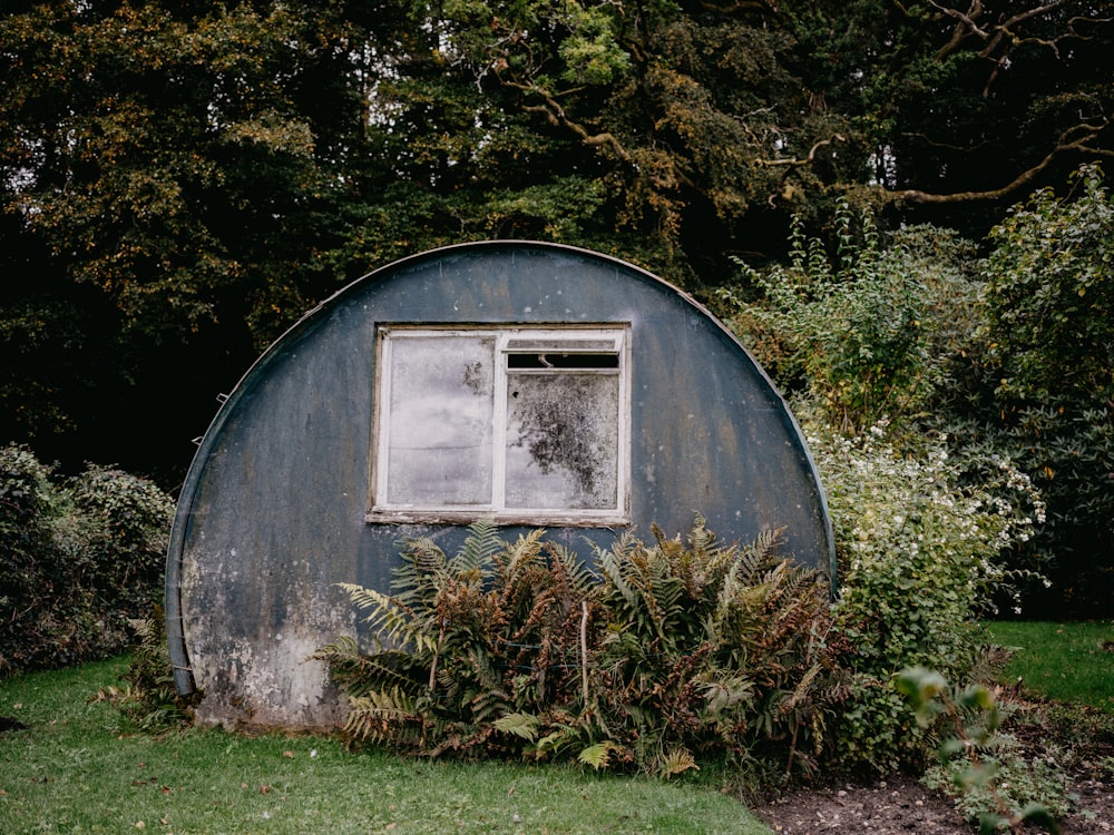 ein rundes Gebäude mit einem Fenster mitten im Garten