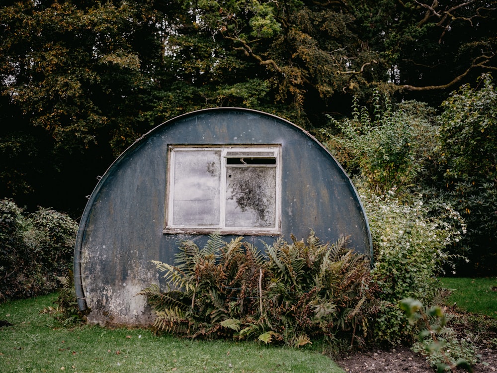 a round building with a window in the middle of a garden