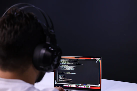A focused learner engaging with a laptop displaying coding and cybersecurity tools.