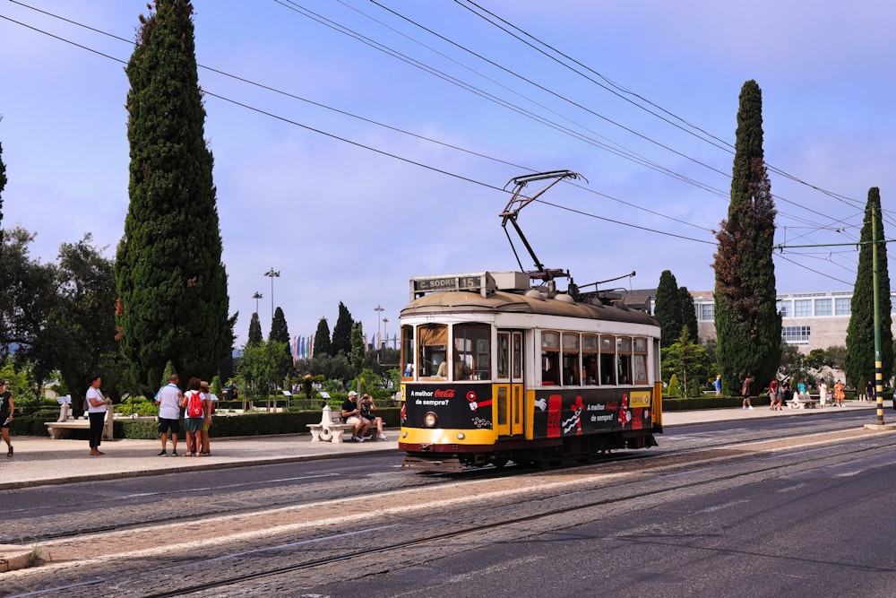 a yellow and red trolley car traveling down a street