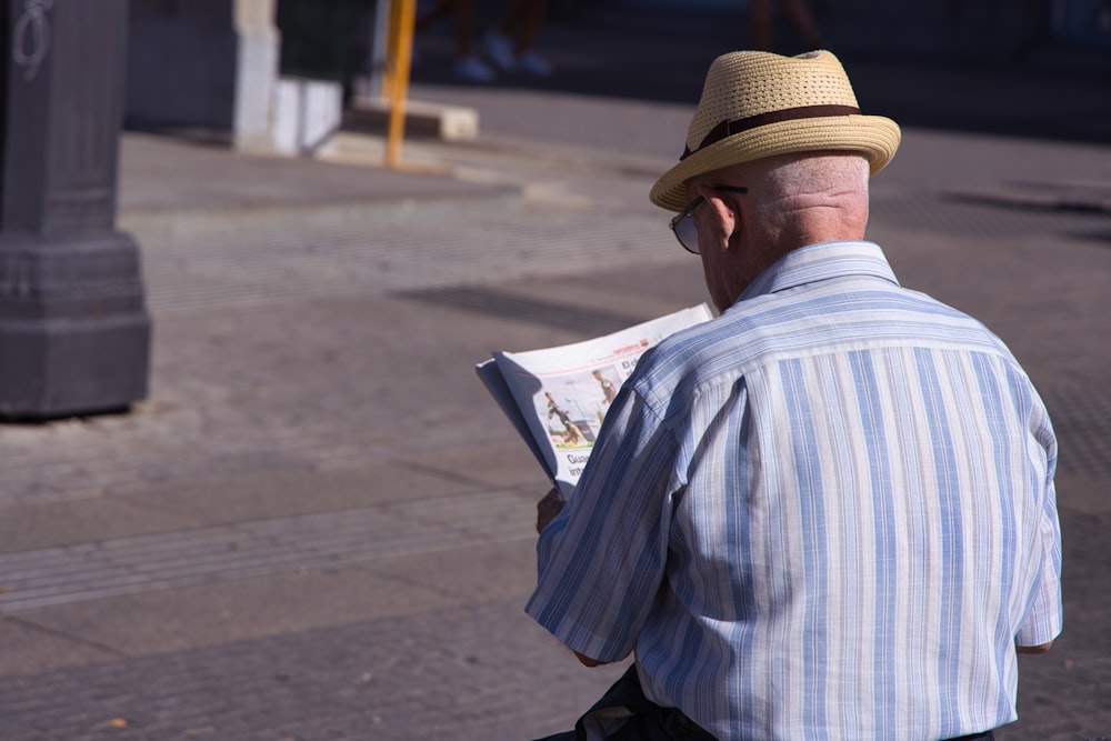 모자를 쓴 남자가 신문을 읽고 있다