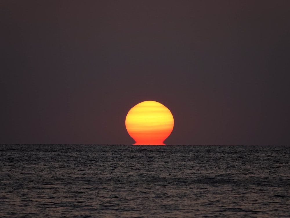 the sun is setting over the ocean as seen from a boat