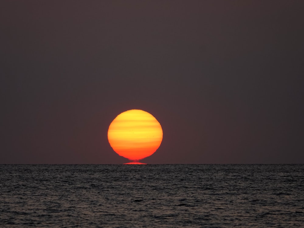 the sun is setting over the ocean as seen from a boat