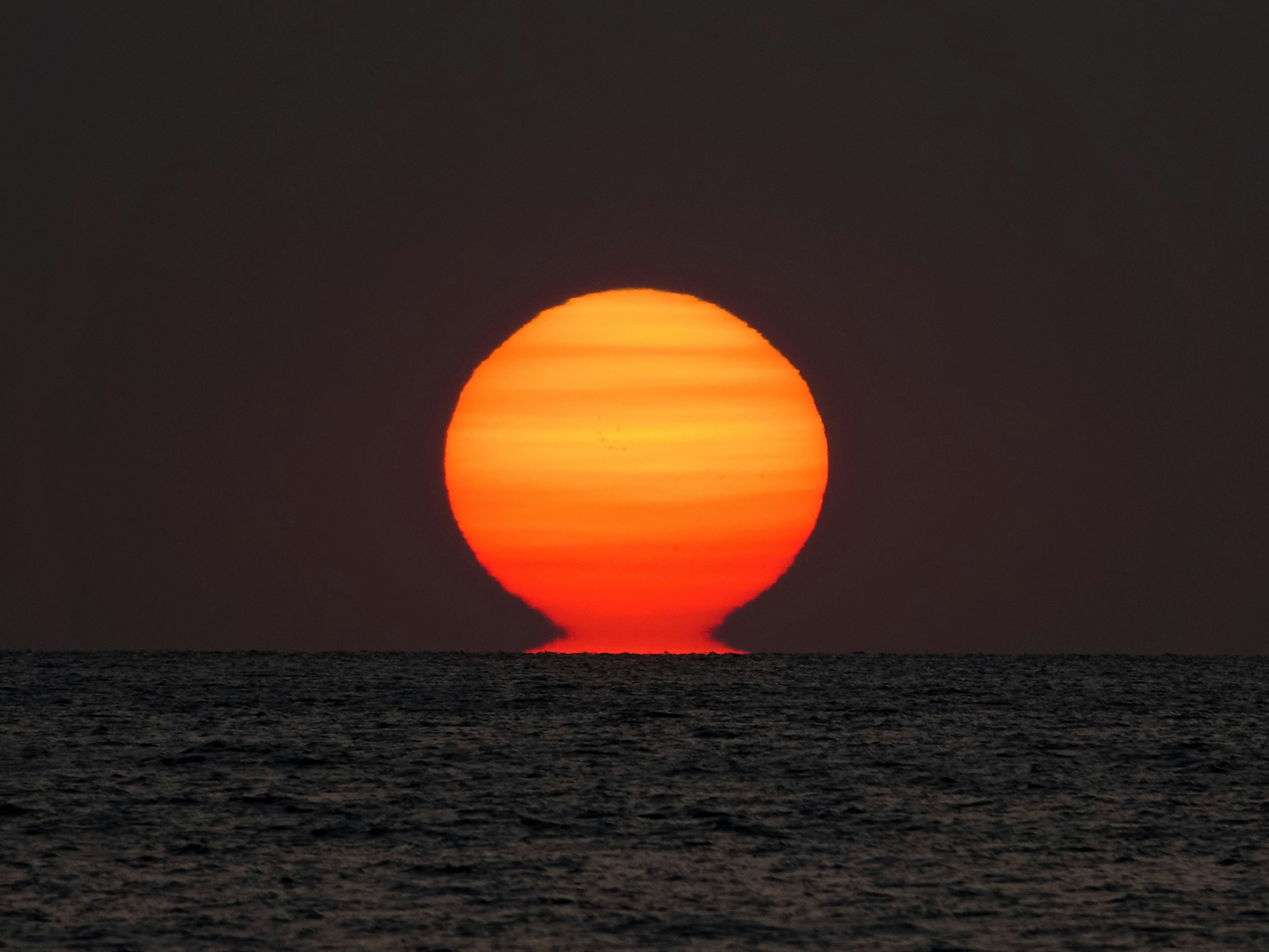 the sun is setting over the ocean as seen from a boat