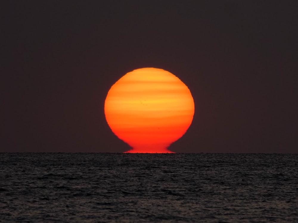 the sun is setting over the ocean as seen from a boat