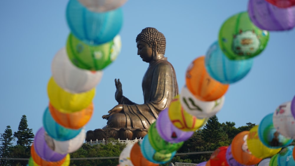 a large buddha statue surrounded by multicolored balloons