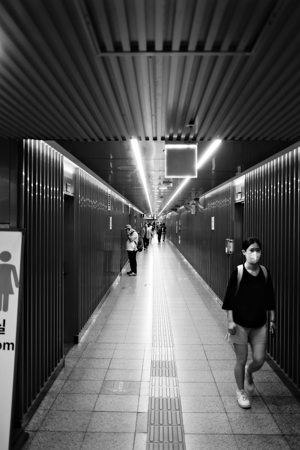 a black and white photo of a woman walking down a hallway