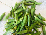Bunches of bright green okra neatly arranged on a rustic wooden crate.