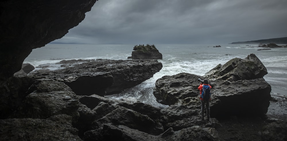 a couple of people standing on top of a rocky beach