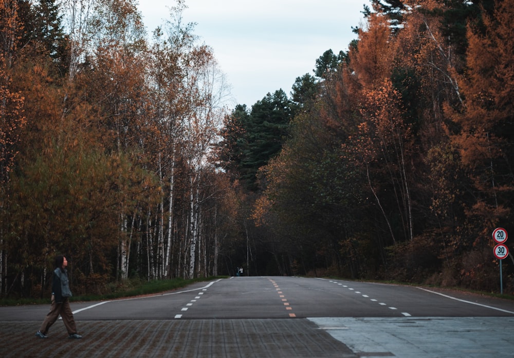 a man walking down a road in the middle of a forest