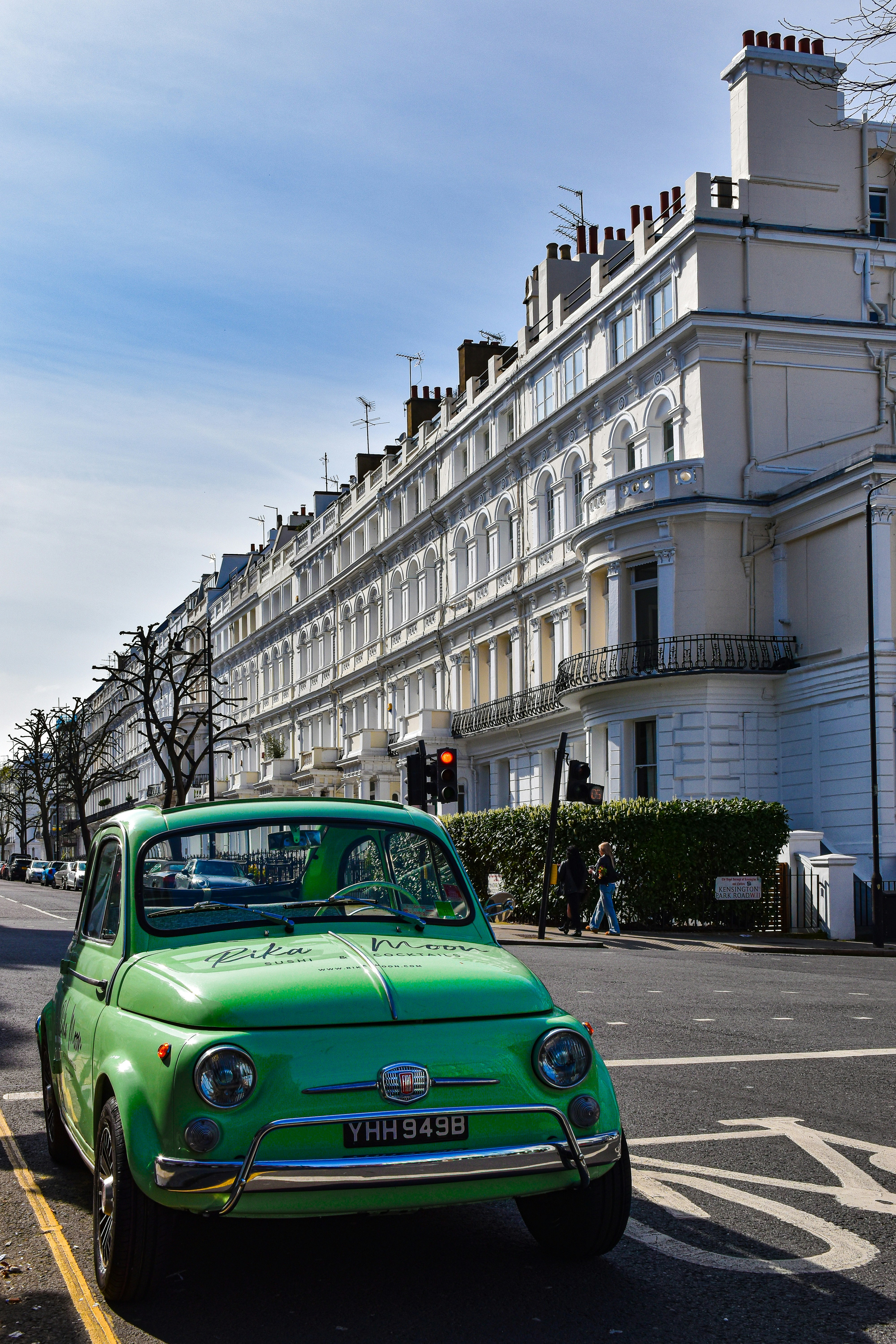 a green car is parked on the side of the road