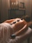 a woman laying on a bed with hot stones on her back