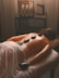 a woman laying on a bed with hot stones on her back
