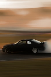 A dynamic shot of a drifting e30 car kicking up smoke on a race track.