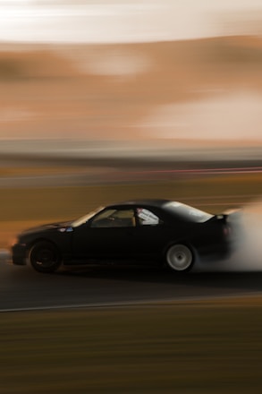 A dynamic shot of a drifting e30 car kicking up smoke on a race track.
