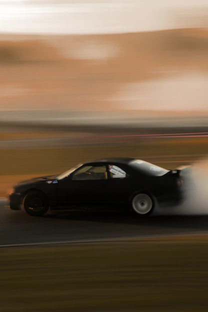 A dynamic photo of a sleek car drifting sharply on a race track, dust and smoke swirling around.