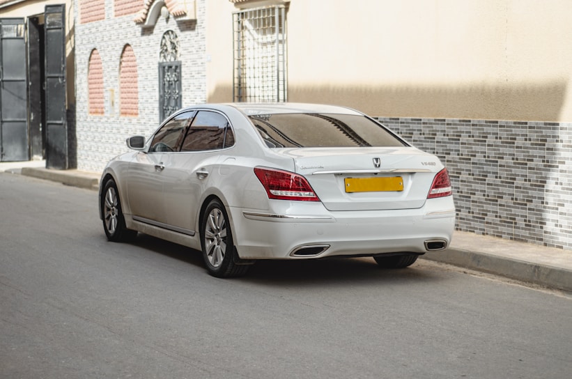 A sleek white sedan parked by a scenic Delhi street, ready for a comfortable ride.