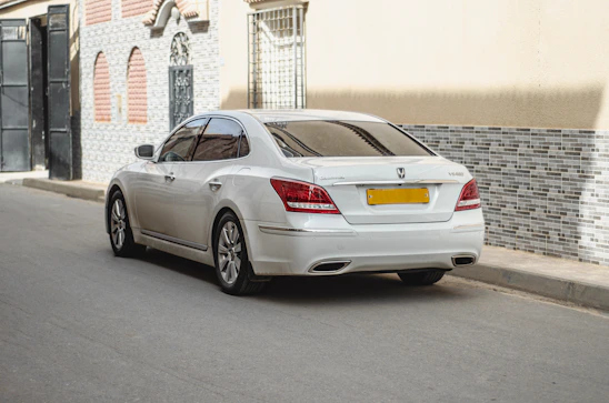 A sleek Ridalux sedan parked by a bustling Delhi street, ready for a comfortable ride.