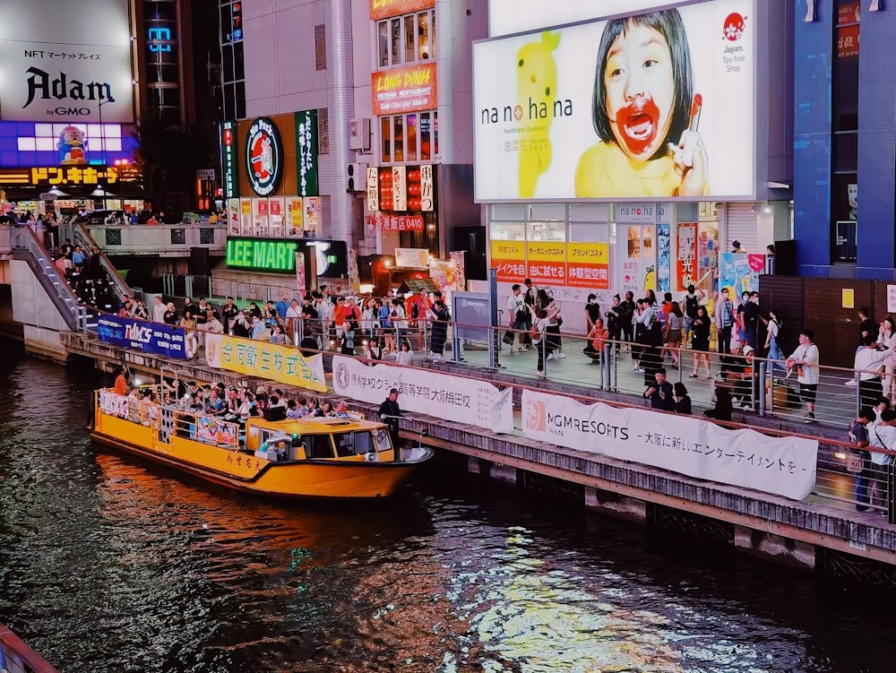 a yellow boat traveling down a river next to tall buildings