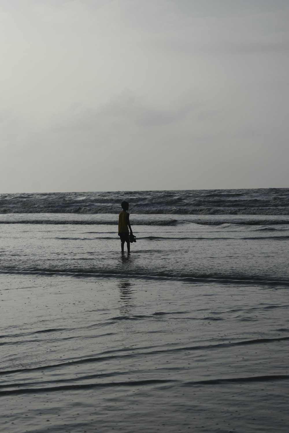 a person standing in the ocean with a surfboard