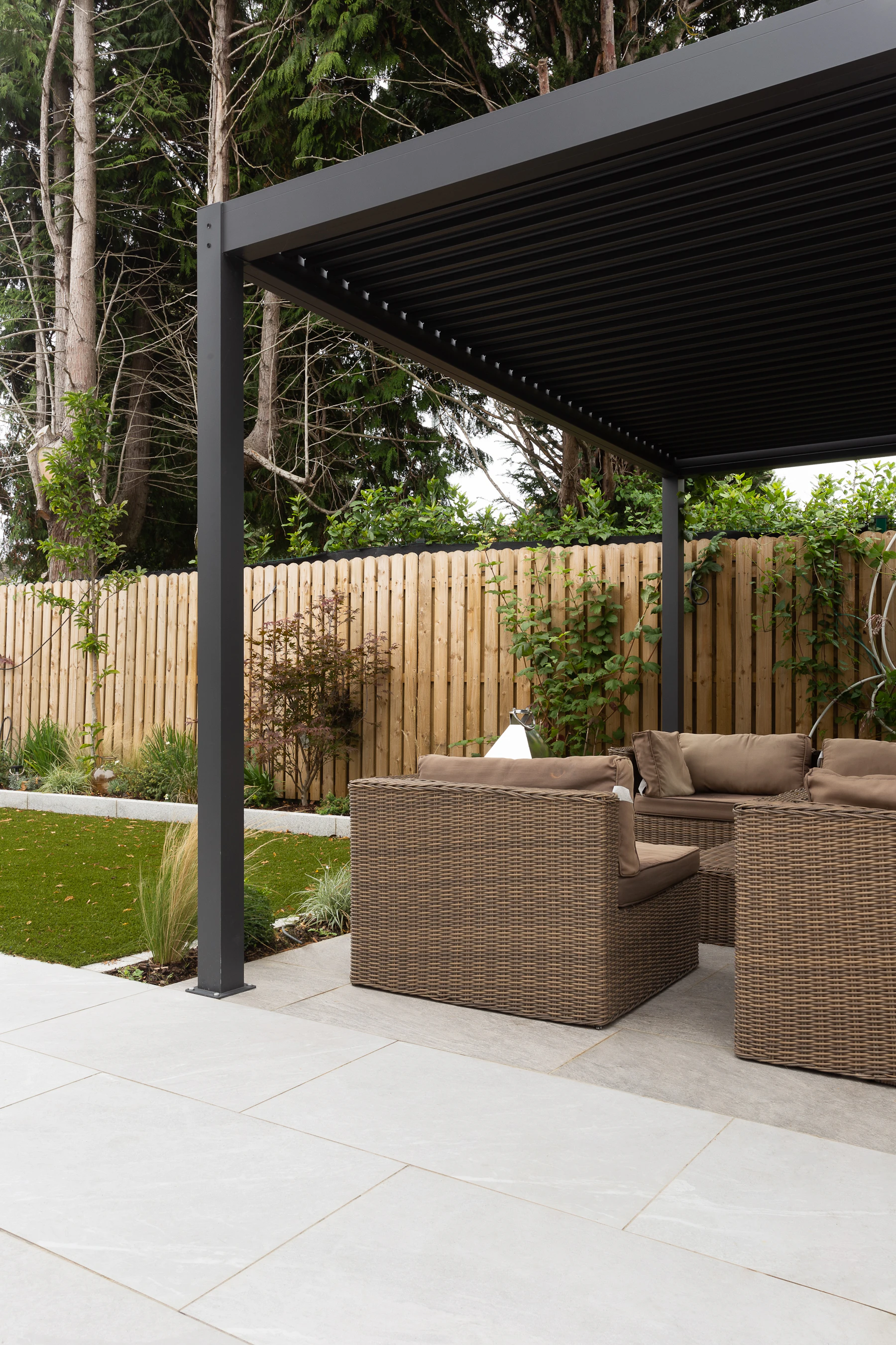 A cedar pavilion with an open side sheltering a seating group above a paved terrace