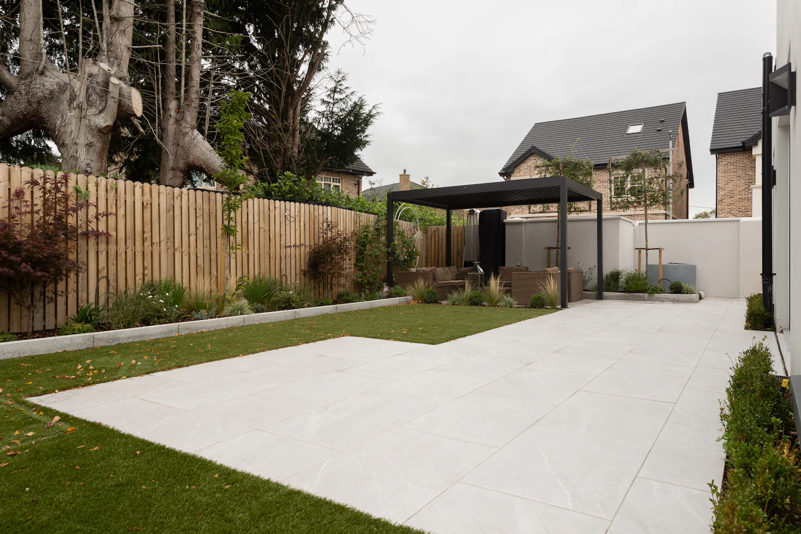 A backyard enclosed by a wooden fence with grass and trees