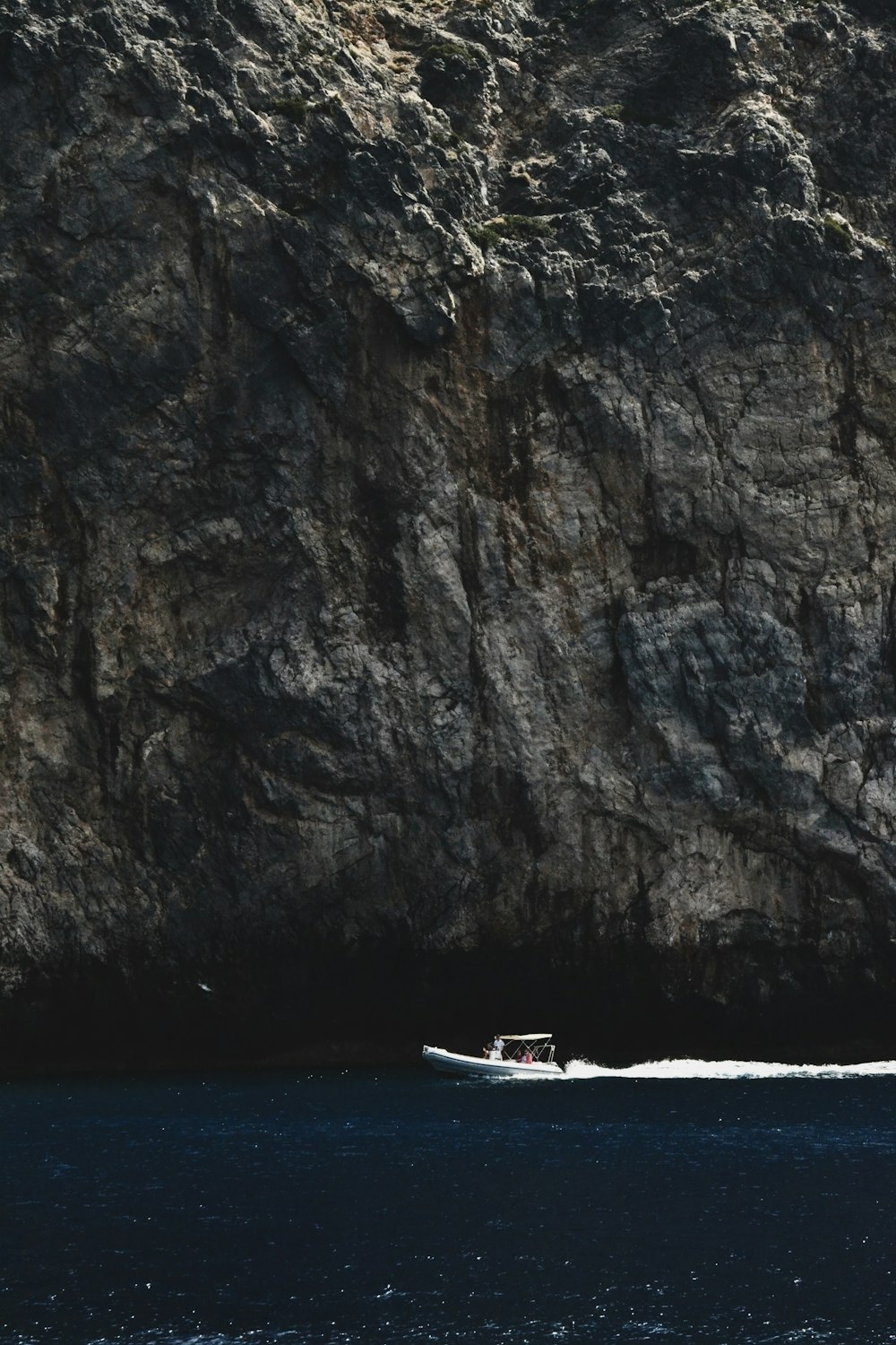 um barco está na água perto de uma grande rocha