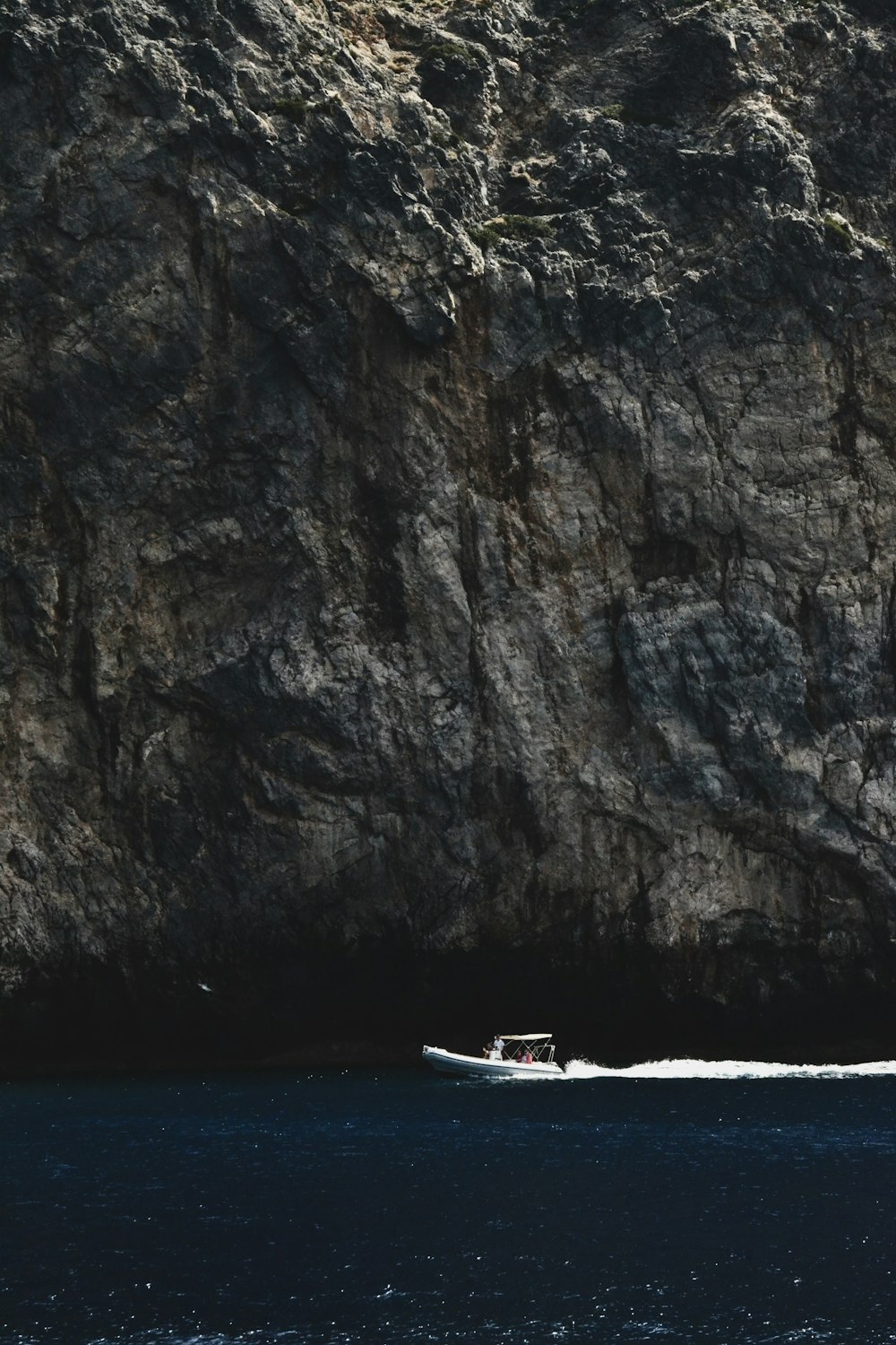 a boat is in the water near a large rock