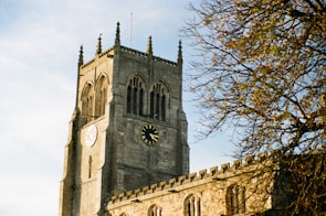 The iconic university clock tower standing tall against a clear blue sky.