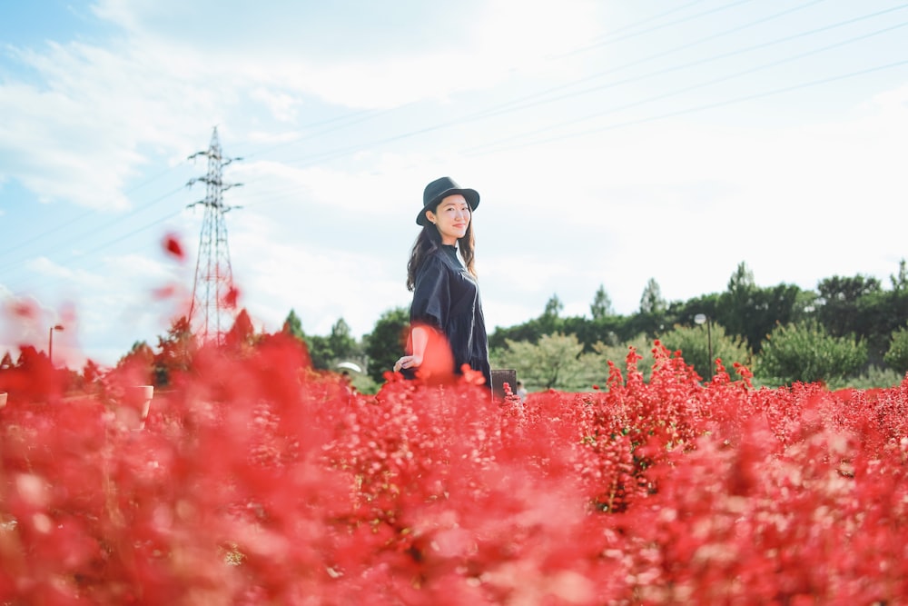 a woman standing in a field of red flowers