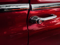 Close-up of a car door being carefully painted with a spray gun