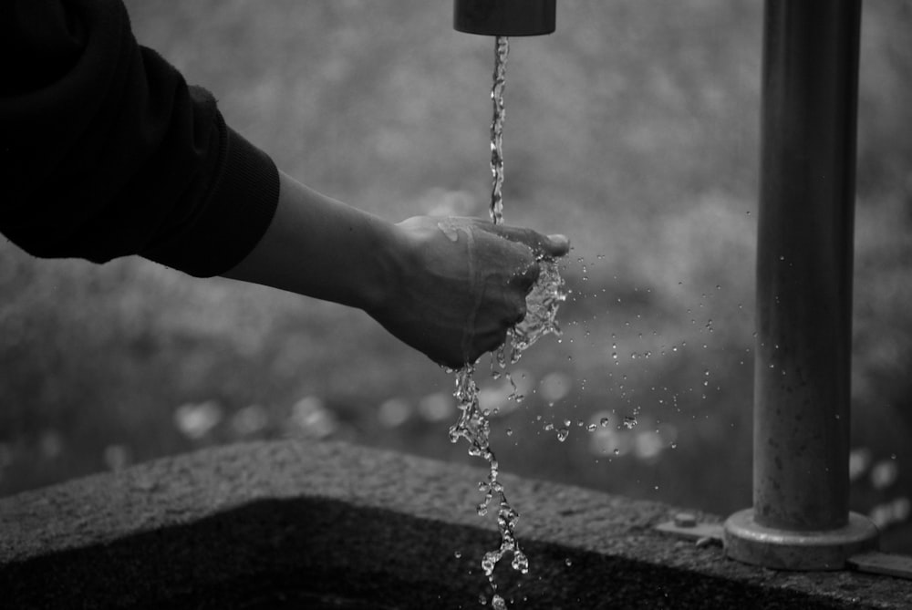 a person is pouring water from a faucet