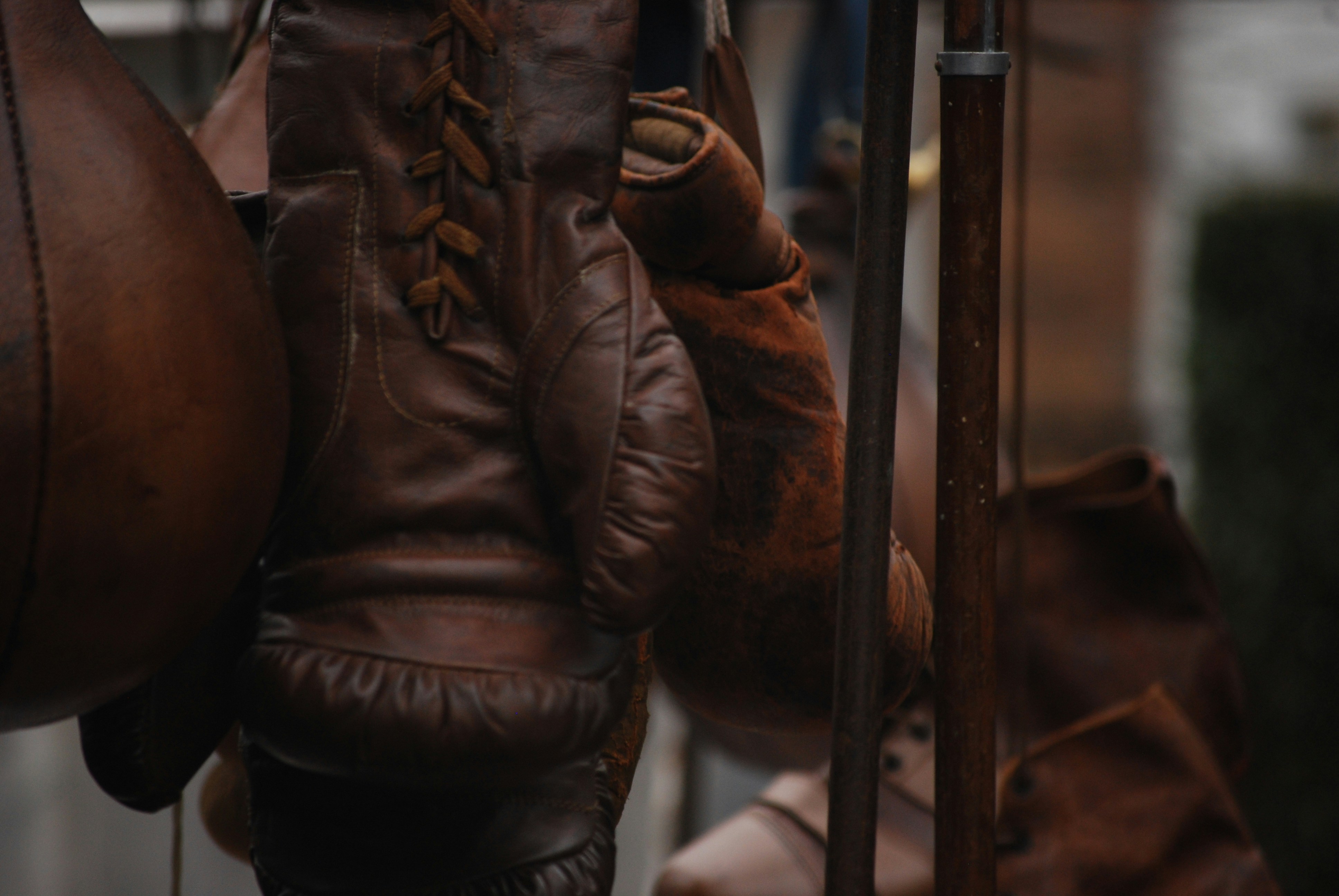 a pair of brown gloves hanging from a pole