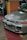 A silver car is parked indoors with a visible license plate reading 'BMM 737'. The vehicle's front grille and hood vents are prominently displayed, and the environment suggests an indoor showroom or parking area with colorful walls in the background.