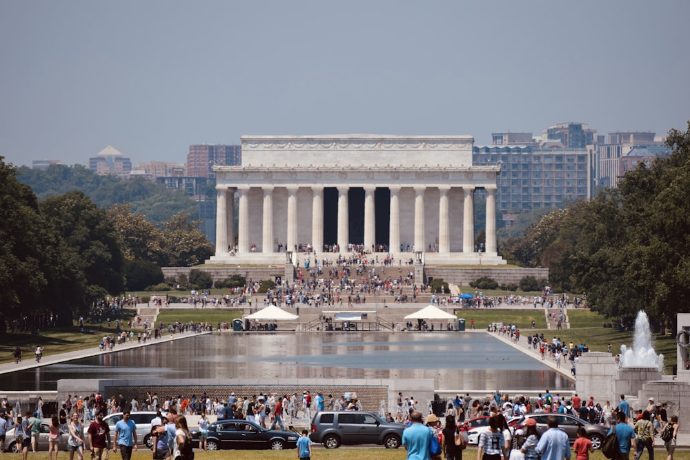 a group of people standing around a fountain in a park