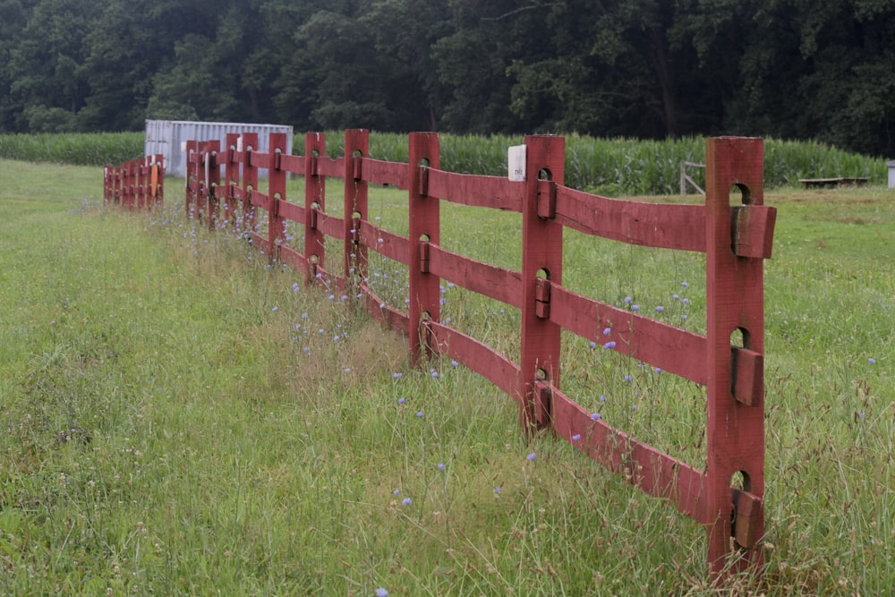 una valla roja en medio de un campo cubierto de hierba