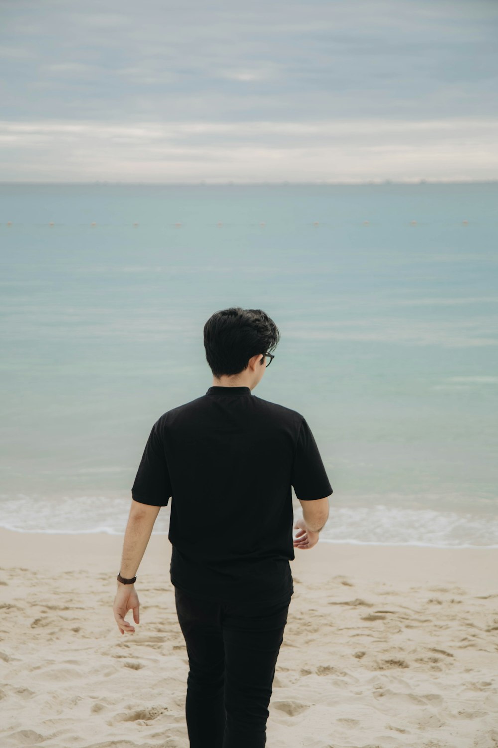 a man standing on a beach next to the ocean