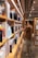 A person in casual clothing stands in a library aisle, browsing through books on the shelves. The shelves are filled with various books, indicating a well-stocked library. The environment appears calm and organized, with warm lighting overhead.