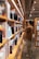 A person in casual clothing stands in a library aisle, browsing through books on the shelves. The shelves are filled with various books, indicating a well-stocked library. The environment appears calm and organized, with warm lighting overhead.