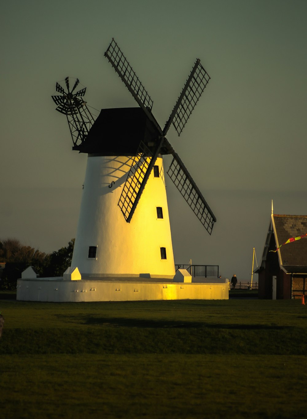 a windmill sitting in a field next to a building