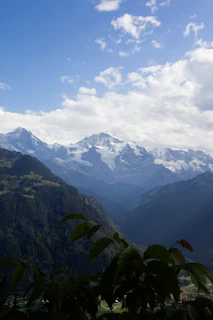 Snow-capped Himalayan mountains towering over lush green valleys under a clear blue sky.