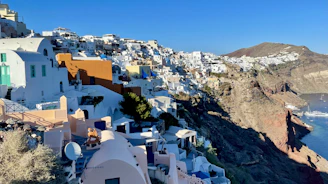 Charming whitewashed houses perched on a cliffside overlooking the deep blue Mediterranean Sea.