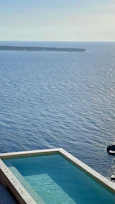 Seaside Pool Villa's infinity pool blending into the ocean horizon under a clear blue sky.