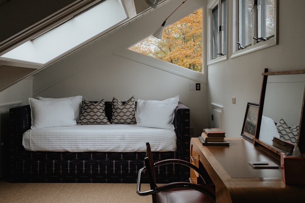 a bed sitting under a window next to a desk