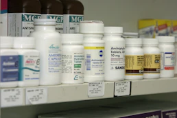 Prescription medication bottles displayed on pharmacy shelves.