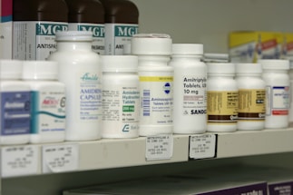 A neatly arranged shelf of various prescription medicines in blister packs and bottles.