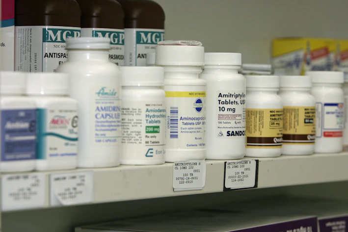 A neatly organized shelf filled with various prescription medicine bottles and boxes.